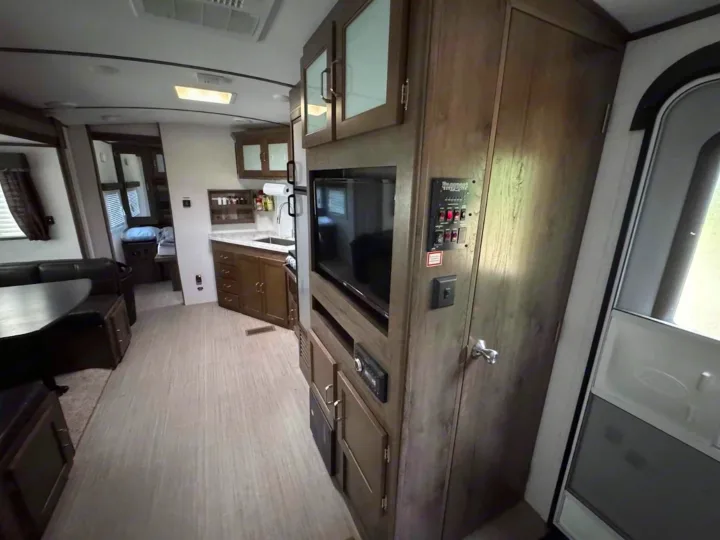 Cozy RV rental interior showcasing a dinette, well-equipped kitchen, and entertainment center with wood cabinets and light flooring.. Keystone RV Passport Grand Touring 2019