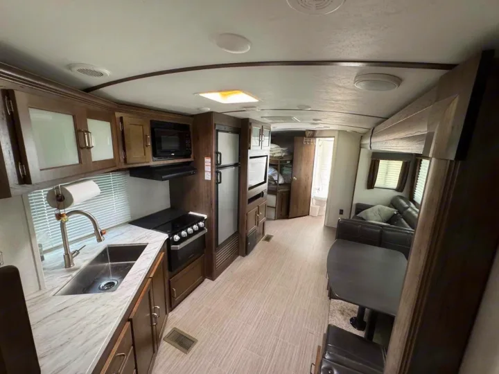 Spacious RV rental interior featuring a full kitchen, dining booth, and living area, perfect for your next adventure.. Keystone RV Passport Grand Touring 2019
