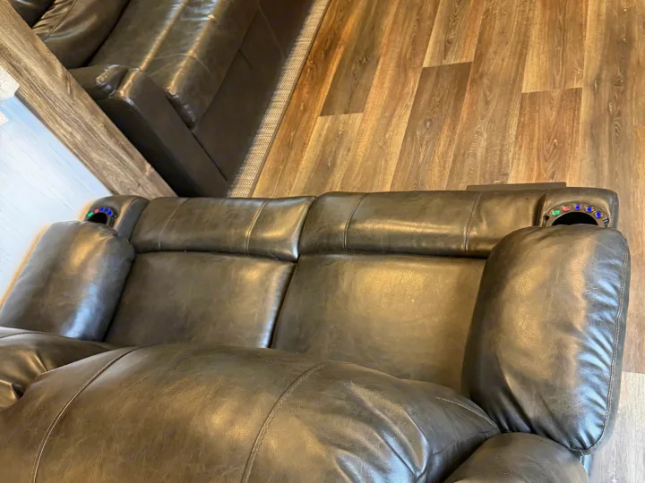 Relax in this RV rental's comfortable dark leather recliner sofa. Features illuminated cup holders and stylish wood flooring.. Heartland RVs Bighorn Traveler 2022
