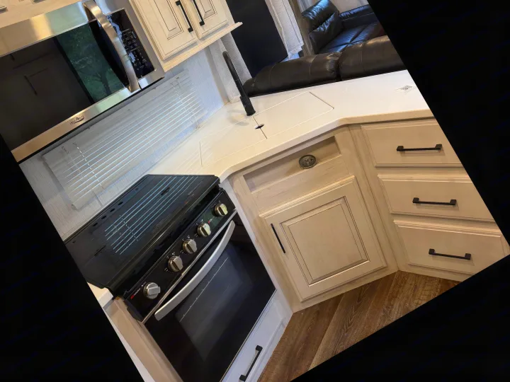 Modern RV rental kitchen featuring a High Pointe microwave, Suburban oven, sleek sink, and light-toned cabinetry.. Heartland RVs Bighorn Traveler 2022