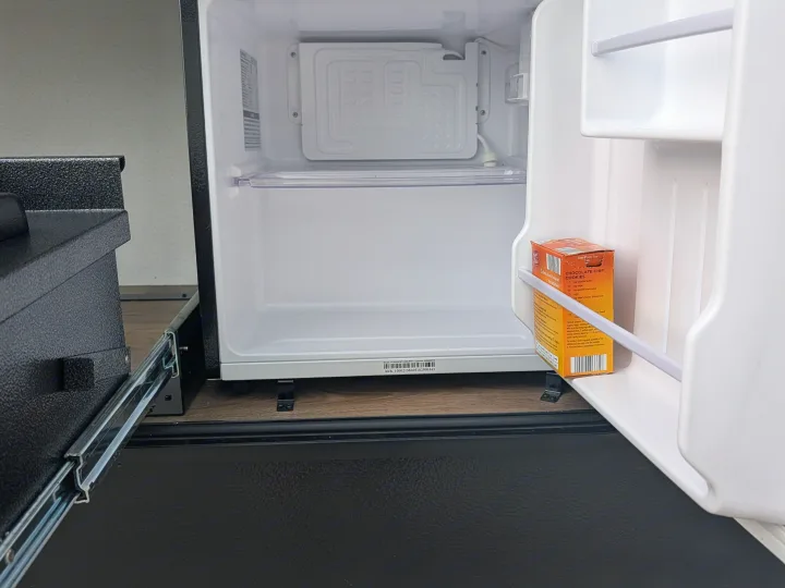 An open mini-fridge in an RV rental, with a chocolate chip cookie mix box on the door, ready for camping trips.. Forest River 303BHCE Camping 2026