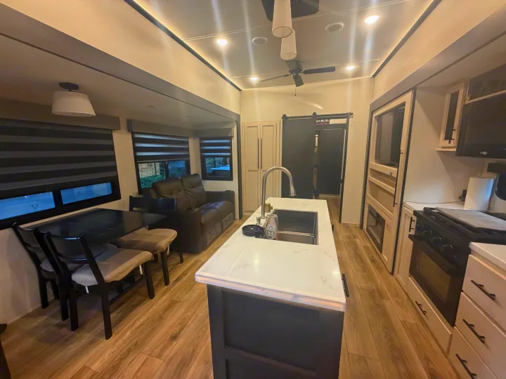 Spacious RV rental interior featuring a modern kitchen island, dining area with table, and comfortable living space.. Forest River Sabre 2025
