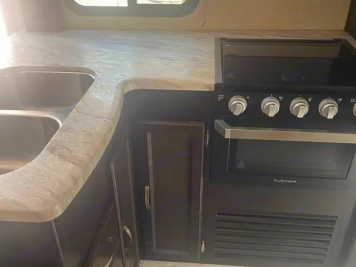 RV rental kitchen: double sink, marbled countertop, and black stove/oven. Ready for your travel adventures.. Coachmen Spirit 2019