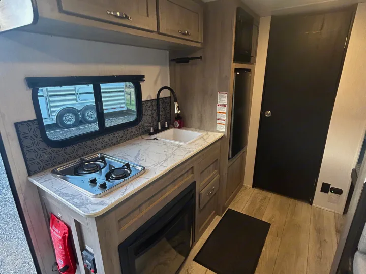 This RV rental features a modern kitchen: two-burner stove, sink, microwave, fridge, and fire blanket for safety.. Cruiser RV A-17BH Avenir 2024