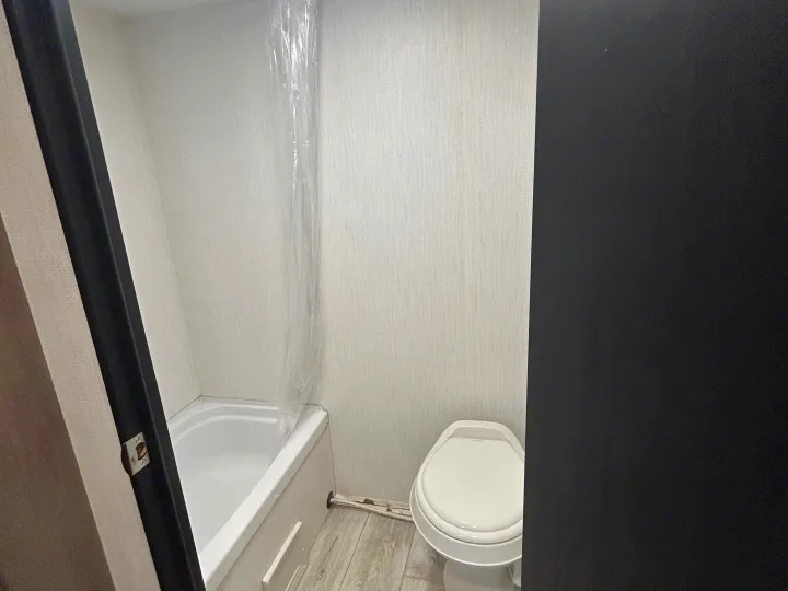 Compact RV rental bathroom with a shower/tub combo, toilet, and light-colored walls.. Cruiser RV A-17BH Avenir 2024