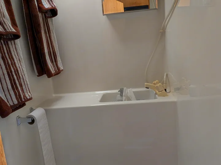 This RV rental's compact bathroom features a shower/tub, striped towels, toilet paper, and toiletries on the tub's edge.. Dodge Dodge 1 Ton Pu 2014