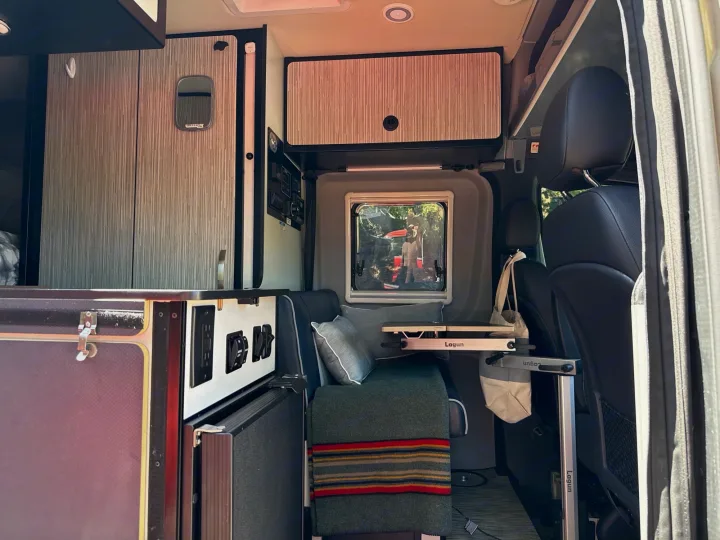 Inside this modern rv rental: custom cabinets, cozy bench seating, Lagun table, and power outlets for comfort on the road.. Winnebago Revel 2022