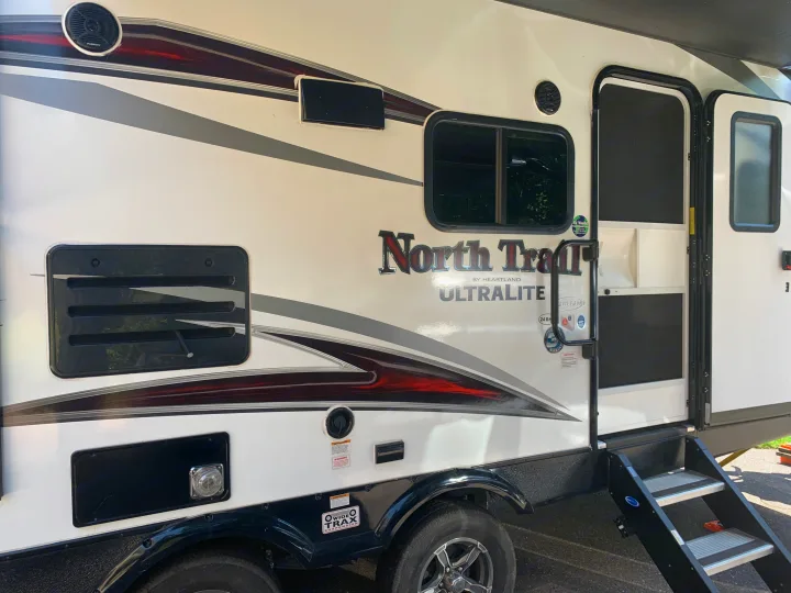 Side view of an RV rental: a "North Trail by Heartland Ultralite" travel trailer exterior with its steps and graphics.. Heartland RVs North Trail 2019