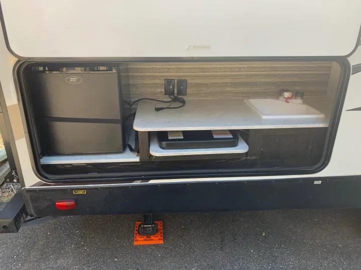 Explore this RV rental's outdoor kitchen, complete with a mini-fridge, sink, and cooktop for easy camping adventures.. Heartland RVs North Trail 2019