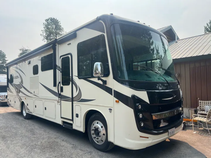 This sleek white and black Class A motorhome RV rental is parked on a gravel lot, ready for its next adventure.. Entegra Coach Vision XL 2021