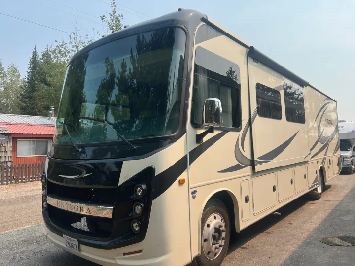 A cream and black Entegra Vision RV rental, a Class A motorhome, parked outdoors, ready for your next road trip adventure.. Entegra Coach Vision XL 2021
