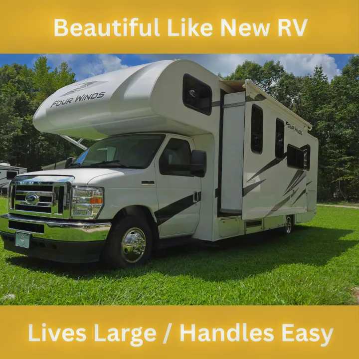 Explore in this Four Winds Class C rv rental. A white RV with black graphics, parked on green grass, ready for easy travel.. Thor Four Winds 2024