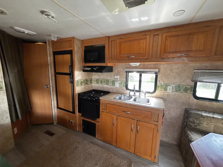 Inside this rv rental: a well-equipped kitchen with stove, microwave, double sink, and refrigerator, plus dinette seating.. Coachmen Spirit of America 2009