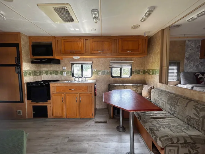 Clean RV rental interior featuring a full kitchen, dinette with seating, and wood-look flooring. Ready for your next adventure!. Coachmen Spirit of America 2009