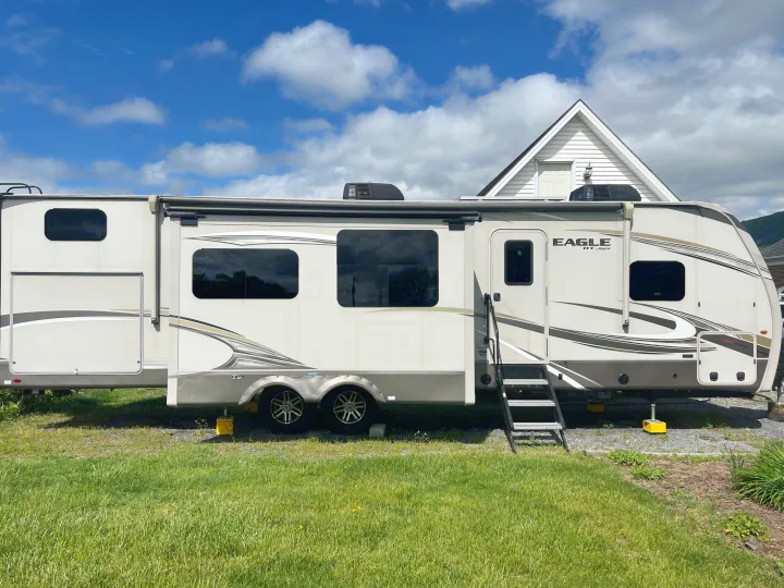 Modern fifth-wheel rv rental with extended slide-outs & steps, parked on grass on a sunny day, ready for adventure.. Jayco Eagle HT 2020