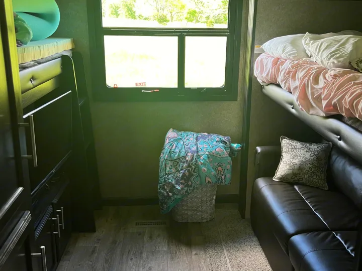 RV rental interior: bunk beds with bedding, a window with 'EXIT' label, and a comfortable sofa with a patterned pillow.. Jayco Eagle HT 2020