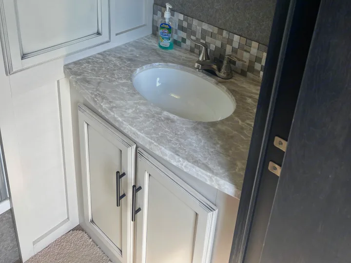 Modern RV rental bathroom vanity featuring a gray marble-look counter, white sink, and light gray cabinets.. Jayco Eagle HT 2020