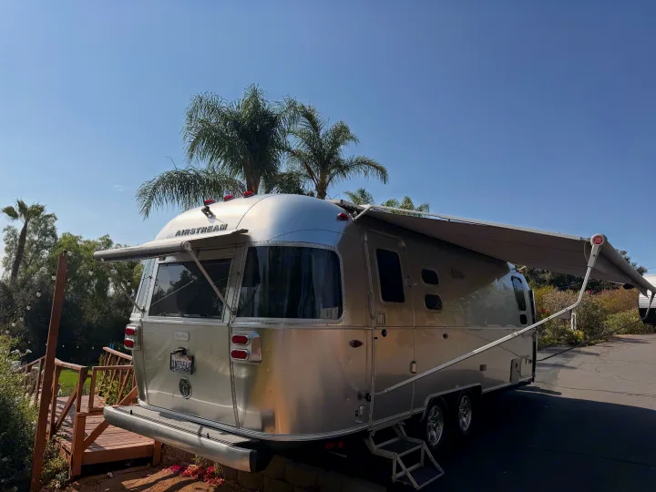 A silver Airstream travel trailer with an extended awning, ready for your next rv rental adventure under sunny skies.. Airstream Flying Cloud 2022