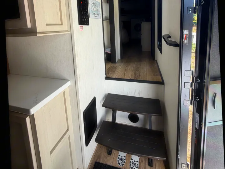 rv rental interior: Entrance steps, kitchen cabinets, a control panel, and a hallway revealing a washing machine.. Forest River Sabre 2025