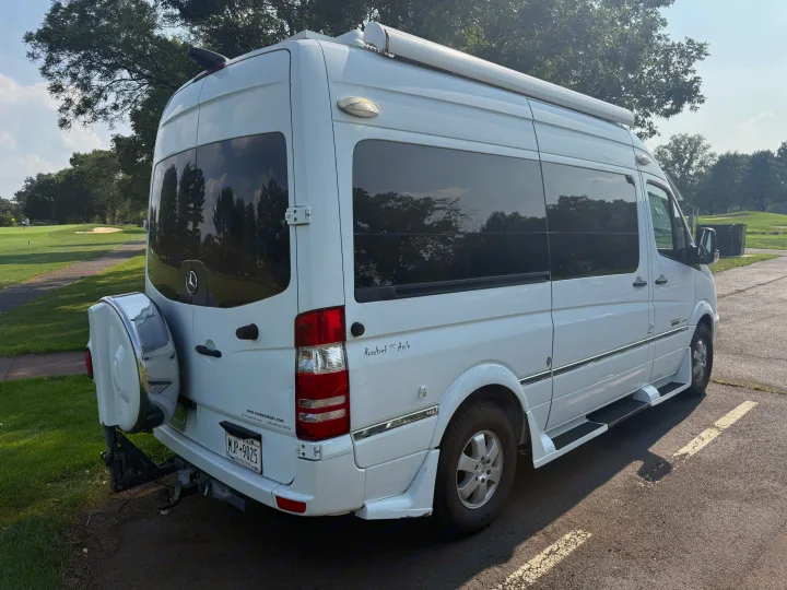 White Roadtrek SS Agile RV rental (Mercedes-Benz Sprinter camper van) parked by a sunny golf course.. Roadtrek Roadtrek Class B 2014