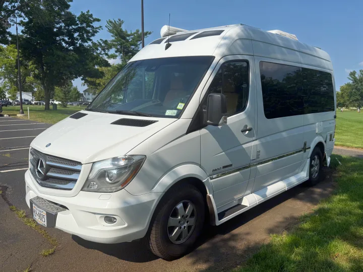 A white Mercedes-Benz Sprinter RV rental, a premium camper van, seen parked in sunny weather.. Roadtrek Roadtrek Class B 2014