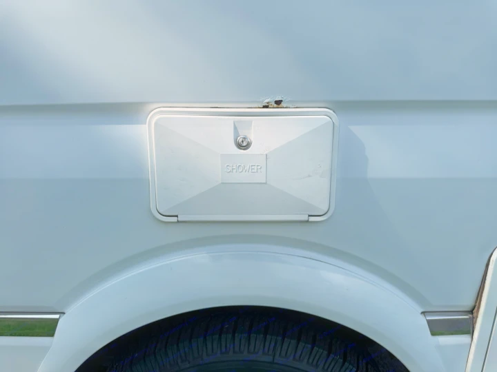 RV rental exterior: white shower access panel with lock, significant rust above, and chrome trim detail.. Roadtrek Roadtrek Class B 2014