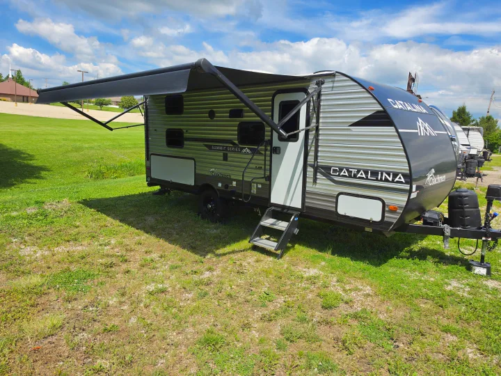 Spacious Catalina Summit Series travel trailer with an extended awning, perfect for an RV rental adventure on a sunny day.. Coachmen 184BHS 2024
