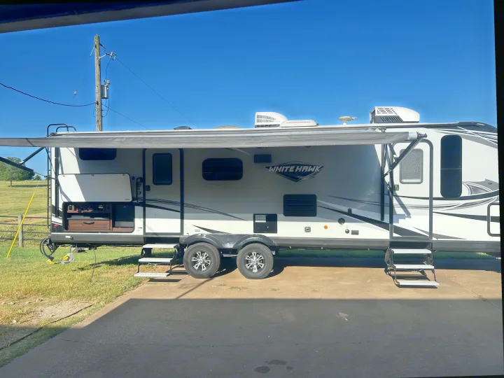 White Hawk RV rental with awning extended, open outdoor kitchen, and steps deployed on a sunny day.. Jayco White Hawk 2019