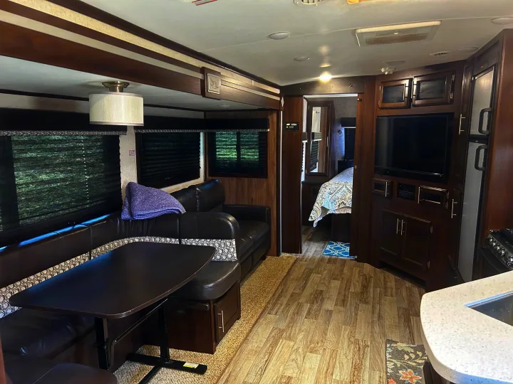 Spacious RV rental interior with dinette, entertainment center, and peek into the bedroom. Perfect for travel!. Jayco White Hawk 2019