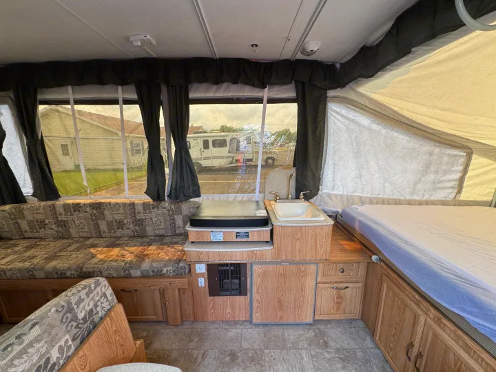 RV rental interior: pop-up camper with kitchenette, patterned dinette, and bed area for your adventures.. Forest River Yearlying 4100 2008