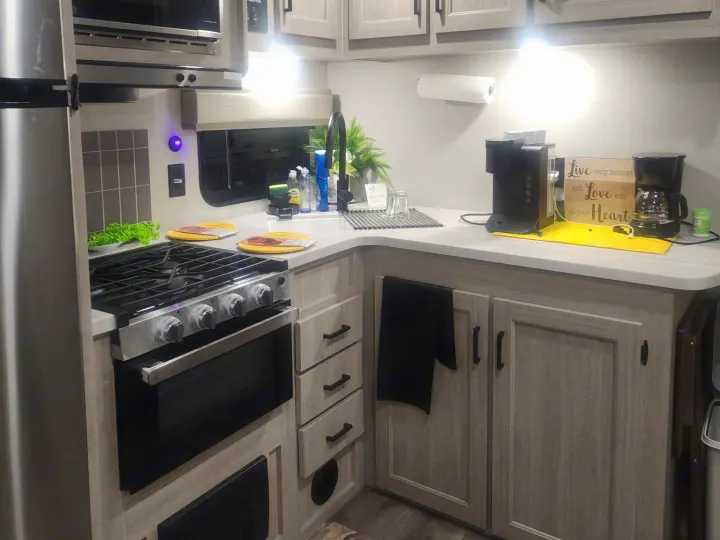 Stylish RV rental kitchen with stainless appliances, ample storage, and a coffee station on the counter.. Coachmen 29THS 2025