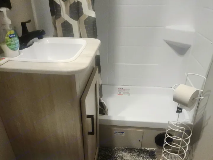 This RV rental bathroom features a compact toilet, vanity with sink, and a shower/tub combo, complete with a cozy bath mat.. Coachmen 29THS 2025