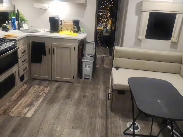 Bright rv rental interior featuring a kitchenette with sink/stove, dinette with table/benches, and wood-look floor.. Coachmen 29THS 2025