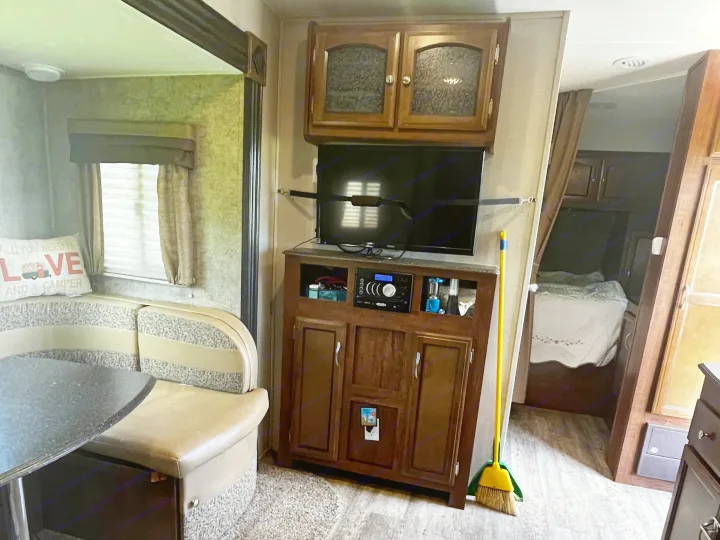 Cozy RV rental interior featuring a dinette, entertainment center, and a peek into the bedroom for comfortable travel.. Coachmen Freedom Express 2017