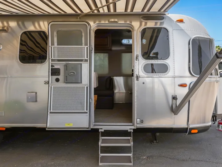 Silver Airstream RV rental with open door and steps, showing the cozy interior. Perfect for your next road trip adventure!. Airstream Classic 2019