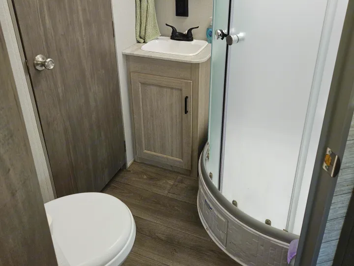 Compact RV rental bathroom: features a toilet, sink vanity, and curved shower, maximizing space for comfortable travel.. Coachmen Catalina Legacy 2024