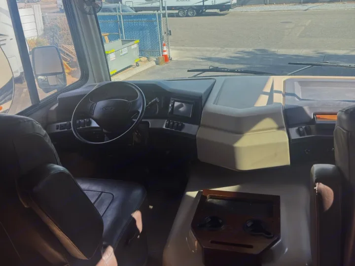 Inside an RV rental, showing the driver's cockpit with a steering wheel, dashboard, and a view of the road ahead.. Fleetwood 35 K 2017