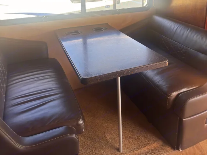 RV rental dinette featuring a speckled dark table with cup holders and cozy brown leatherette booth seating.. Fleetwood 35 K 2017