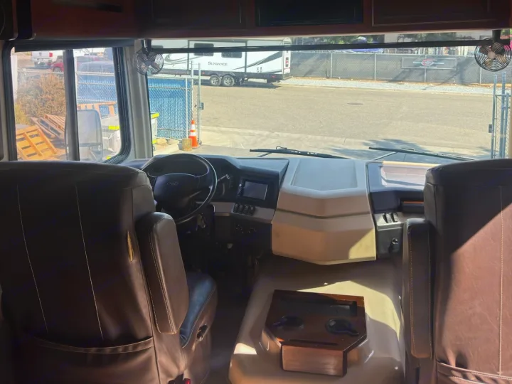 Interior of this RV rental's driver area, showing the steering wheel, dashboard, and brown captain's seats.. Fleetwood 35 K 2017