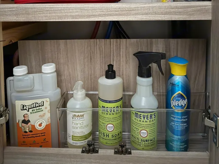 RV rental cleaning & toilet treatment essentials organized in a cabinet: Mrs. Meyer's, Pledge, hand sanitizer.. Winnebago Access 2024