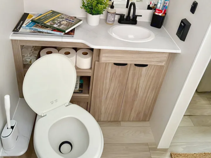 Inside a well-organized rv rental bathroom, featuring a toilet, sink, toiletries, and practical under-vanity storage.. Winnebago Access 2024
