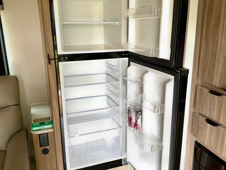 Inside an rv rental: a bright, clean, two-door refrigerator/freezer with clear shelves, ready to be stocked for your next trip.. Winnebago Access 2024