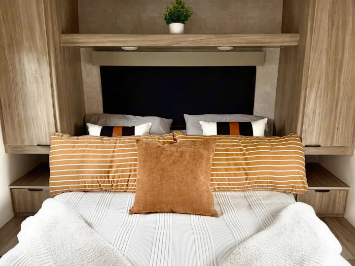 Our RV rental offers a cozy, comfortable bedroom with a neatly made bed, stylish pillows, and convenient storage.. Winnebago Access 2024