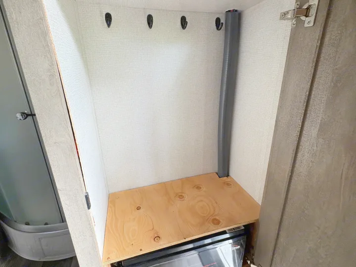 RV rental storage: a compact closet with wall hooks, a wooden shelf, and a utility pipe for organized living.. Imperial Outdoors XploreRV 2022
