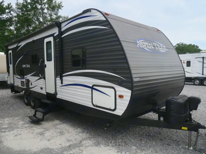 Aspen Trail travel trailer for RV rental, featuring its gray and white exterior, two doors, and front hitch setup.. Aspen Trail Aspen Trail Trailer 2018
