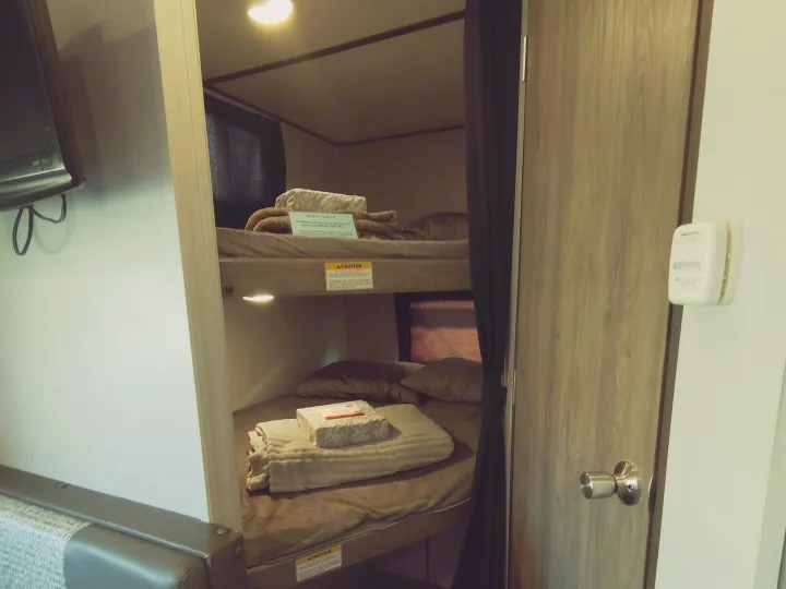 Cozy RV rental bunk beds, fully made with bedding and clear instructions, offering a comfortable sleeping area.. Crossroads RV Zinger Lite 2020