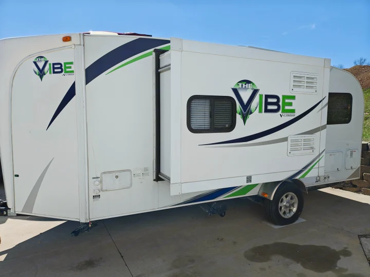 Vibe V-Cross travel trailer RV rental with pop-out extended. This white camper is parked on concrete, ready for adventure.. Forest River V-Cross Vibe 2012