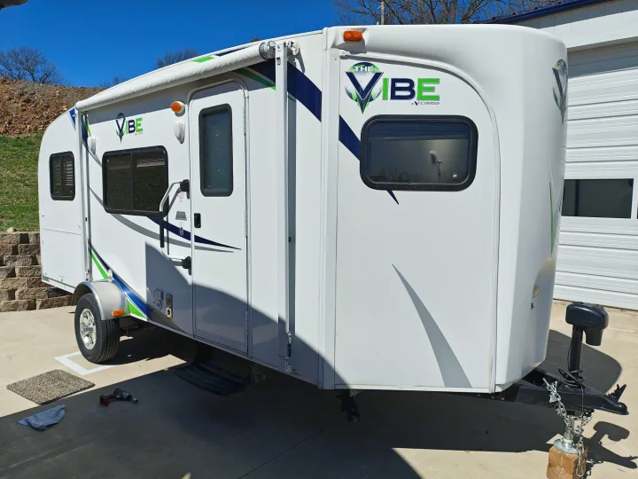 This white 'The Vibe by V-Cross' RV, ideal for an rv rental, with green & blue graphics, parked on a concrete slab.. Forest River V-Cross Vibe 2012