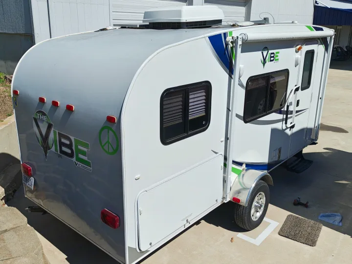 A bright Vibe V-Cross RV rental, a compact travel trailer with green accents, parked outdoors, ready for adventure.. Forest River V-Cross Vibe 2012