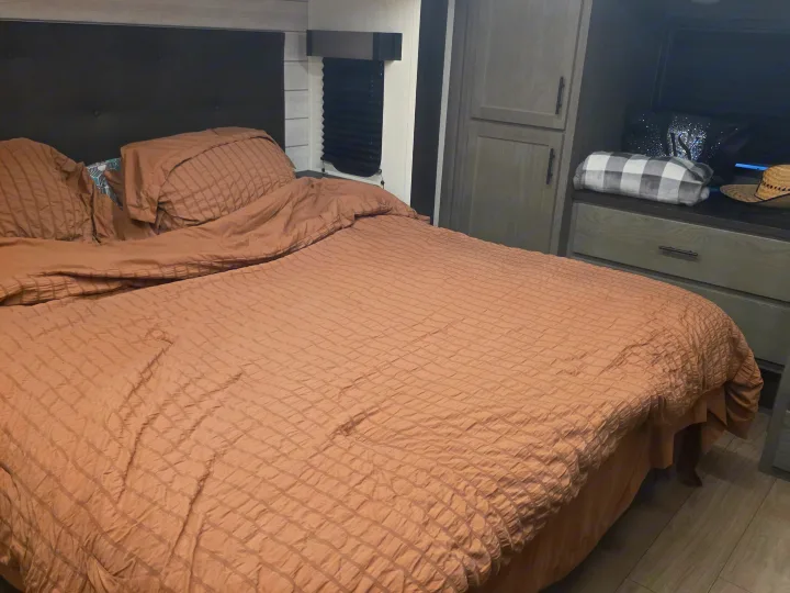 Cozy RV rental bedroom with a comfy bed, textured bedding, headboard, wardrobe, and a dresser.. Forest River Cherokee Alpha Wolf 2026